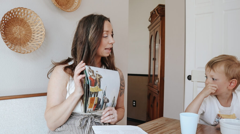 Christian homemaker sits at the table and reads a book to her children.